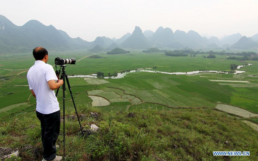 A man takes photo of the rural scenery in Guzhai Village of Liucheng County, south China's Guangxi Zhuang Autonomous Region, May 21, 2013. (Xinhua/Deng Keyi) 