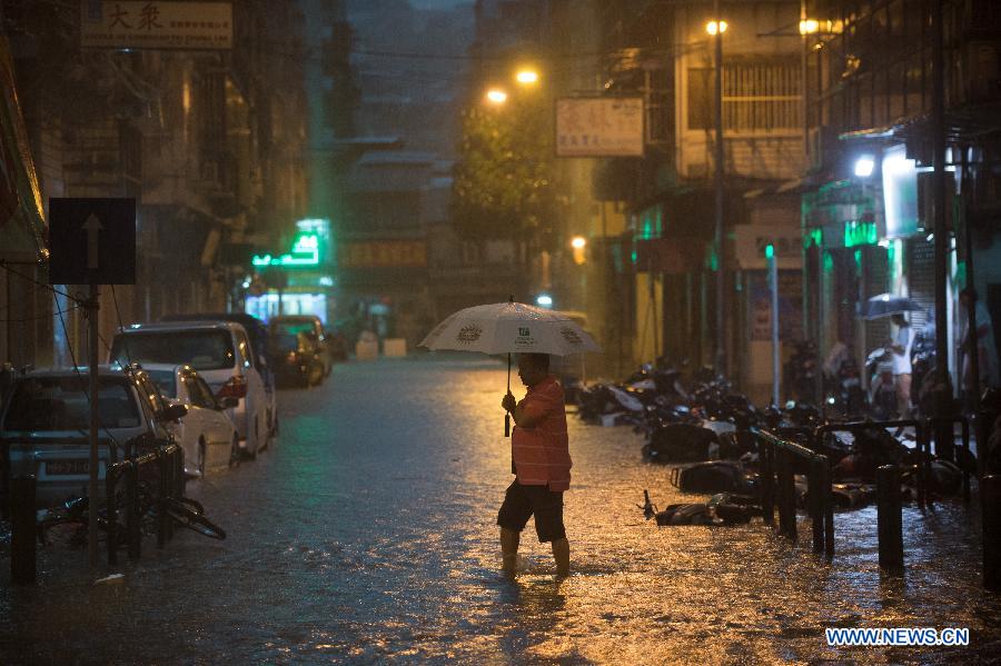 A pedestrian walks in rain on a waterlogged road in Macao, south China, May 22, 2013. (Xinhua/Cheong Kam Ka)