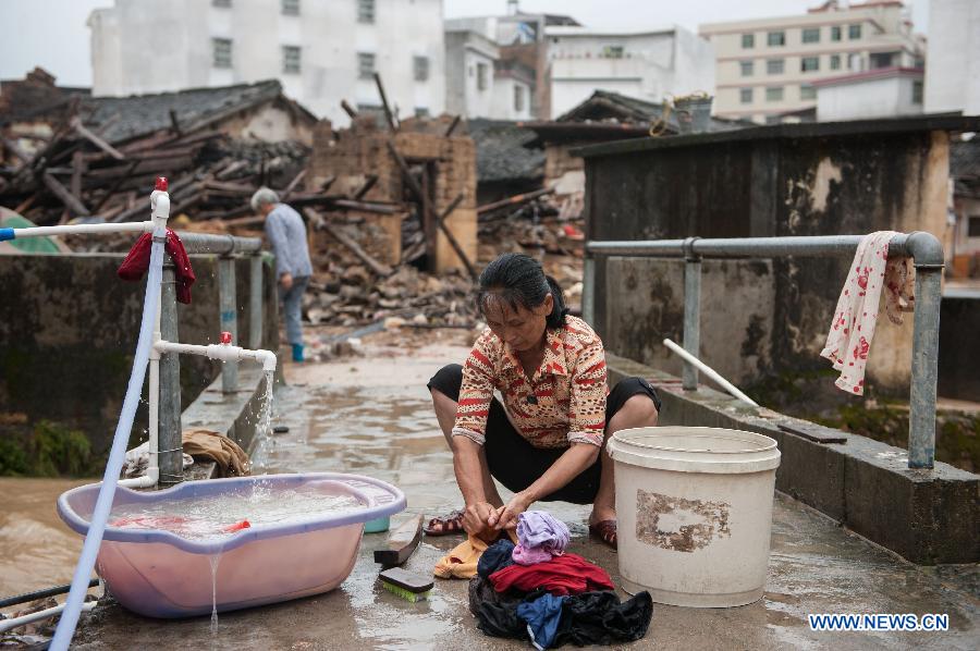 A villager washes clothes in front of houses destroyed by the rainstorm in Guangfu Town of Jiaoling County, Meizhou City, south China's Guangdong Province, May 22, 2013. Meizhou City was hit by a rainstorm on May 19, which killed one people and destroyed 951 houses, leaving 180, 000 people affected in Jiaoling County. (Xinhua/Mao Siqian) 