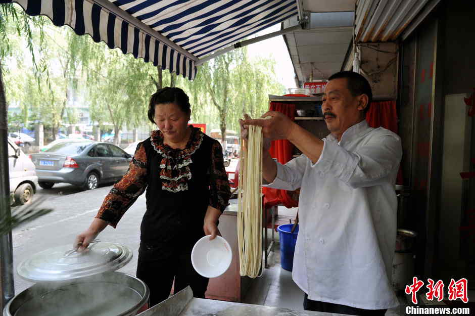 The shop owner serves a bowl of hot noodles for diner in Hefei, the capital city of central China's Anhui province on May 21, 2013. (Photo by Han Suyuan/ Chinanews.com)