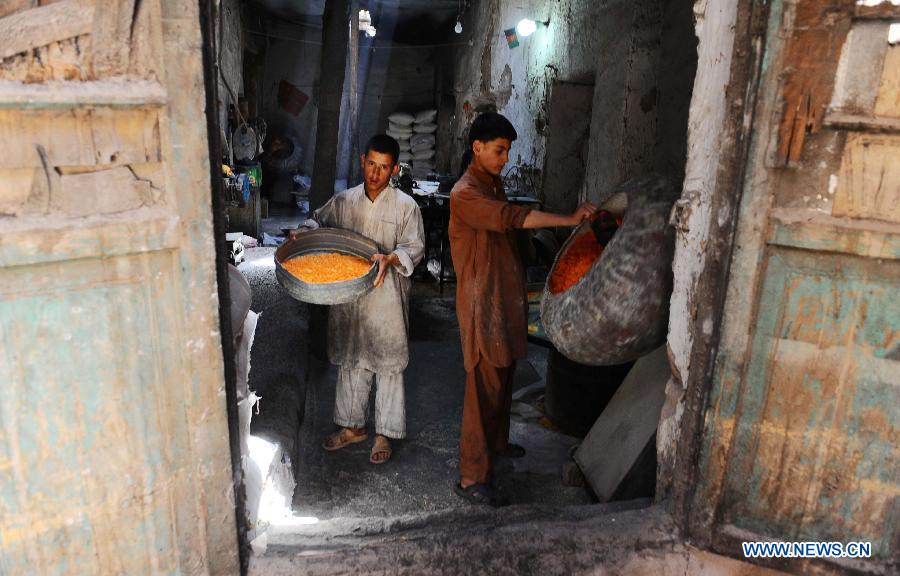 Two Afghan boys work at a traditional sweet factory in Herat province, western Afghanistan, on May 22, 2013. (Xinhua/Sardar)