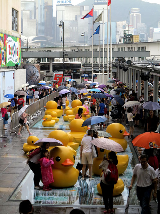 Visitors welcome the duck’s return despite of rain in Hong Kong on May 22, 2013. It was abruptly deflated for maintenance for almost a week. The 16.5-meter-tall duck, conceived by Dutch artist Florentijn Hofman, sailed into the harbor on May 2 to cheering crowds. (Xinhua Photo/ Wang Yuqing). 