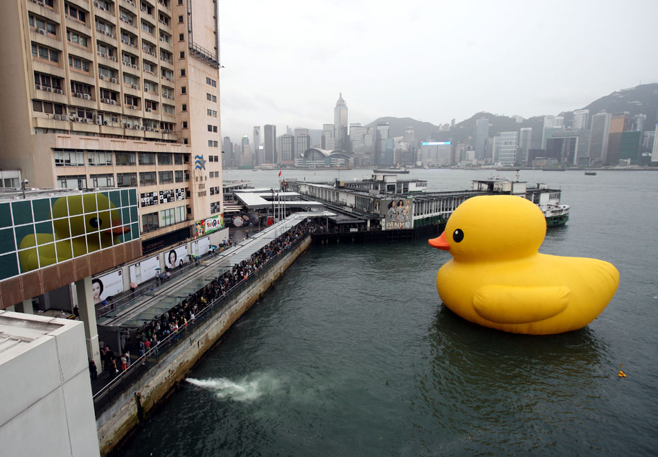 Visitors take photo with the rubber duck in Hong Kong on May 22. 2013. Hong Kong has joyfully welcomed the return of a giant inflatable rubber duck, which drew tens of thousands of visitors before it was abruptly deflated for maintenance for almost a week. (Xinhua Photo/ Wang Yuqing)
