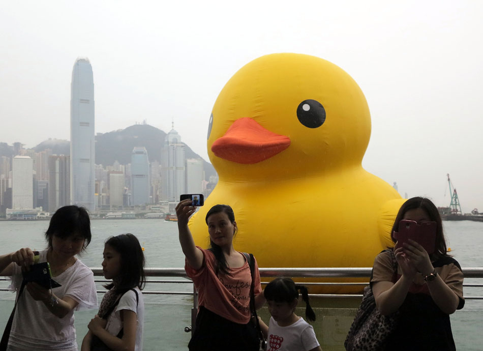 Visitors take photo with the rubber duck in Hong Kong on May 22. 2013. The 16.5-meter-tall inflatable rubber duck is seen at the Victoria Harbor on May 2, 2013. Hong Kong has joyfully welcomed the return of the giant inflatable rubber duck, which drew tens of thousands of visitors before it was abruptly deflated for maintenance for almost a week. (Xinhua Photo/ Wang Yuqing)