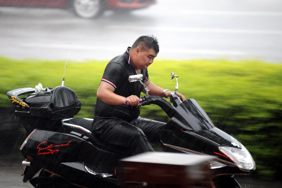 A man rides a motorcycle in the street against the rain in Taiyuan, capital of north China's Shanxi Province, May 22, 2013. Thunderstorms hit the city on Wednesday afternoon. The local meteorological authority issued a yellow warning alert against thunder at 4:15 p.m. local time. (Xinhua)