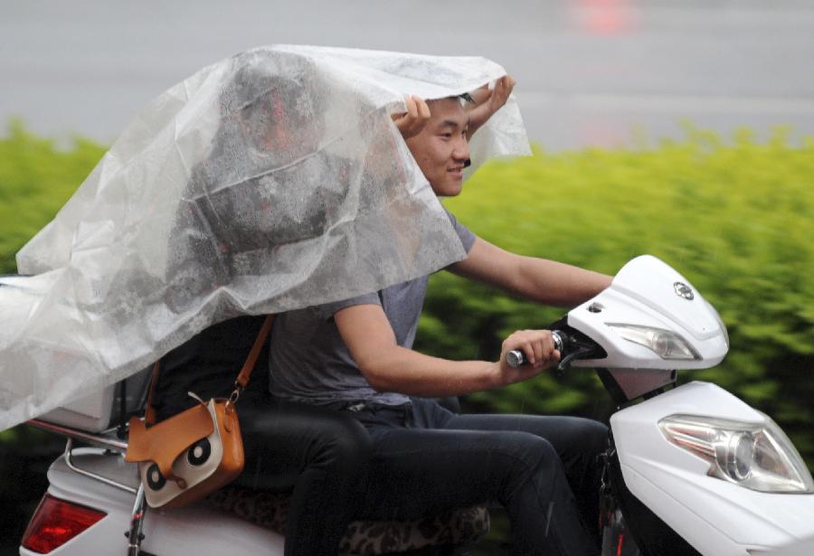 Citizens travel in the street against the rain in Taiyuan, capital of north China's Shanxi Province, May 22, 2013. Thunderstorms hit the city on Wednesday afternoon. The local meteorological authority issued a yellow warning alert against thunder at 4:15 p.m. local time. (Xinhua) 