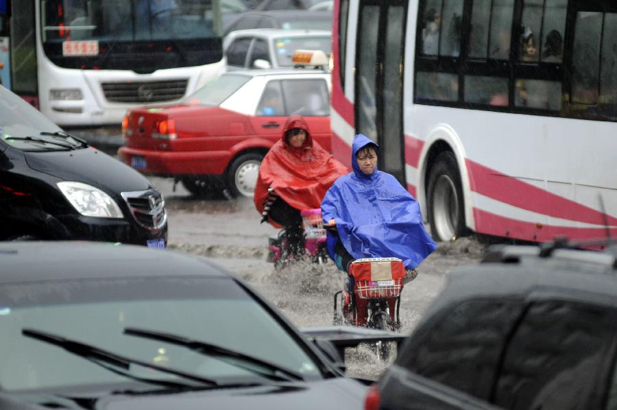 Citizens travel in the street against the rain in Taiyuan, capital of north China's Shanxi Province, May 22, 2013. Thunderstorms hit the city on Wednesday afternoon. The local meteorological authority issued a yellow warning alert against thunder at 4:15 p.m. local time. (Xinhua)