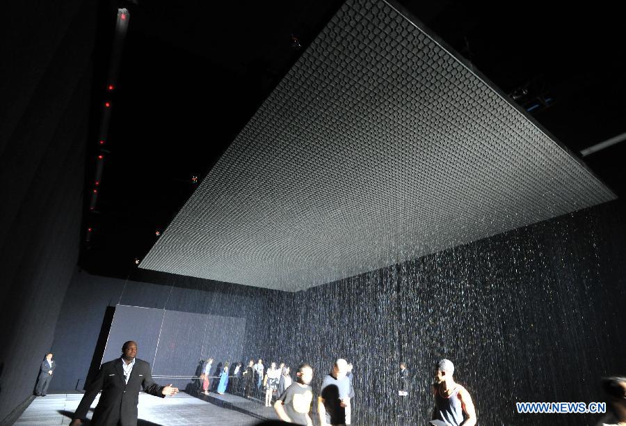 People experience the "Rain Room" art installation by Random International at the Museum of Modern Art in New York, the United States, May 22, 2013. A field of falling water that pauses wherever a human body is detected, "Rain Room" offers visitors the experience of controlling the rain. (Xinhua/Wang Lei)