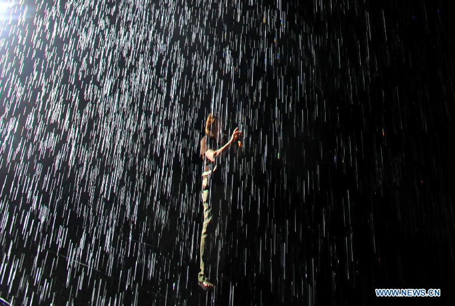 A person experiences the "Rain Room" art installation by Random International at the Museum of Modern Art in New York, the United States, May 22, 2013. A field of falling water that pauses wherever a human body is detected, "Rain Room" offers visitors the experience of controlling the rain. (Xinhua/Wang Lei) 