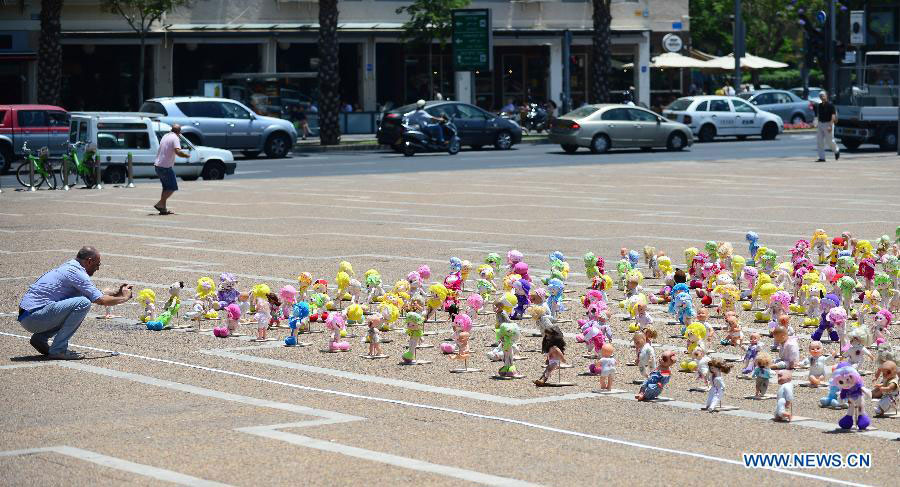 A man takes photos of "abused" dolls at Rabin Square in Tel Aviv, Israel, on May 23, 2013. Approximately 1,000 dolls, made as if they have been abused, were on a display here to arouse public awareness of child abuse and its long-term effect on those victims. (Xinhua/Yin Dongxun) 