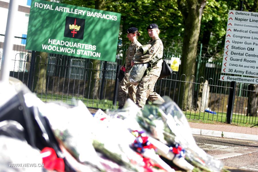 Flowers are laid at the entrance to the Royal Artillery Barracks as two soldiers pass by in Woolwich in southeast London, May 23, 2013. A serving soldier was hacked to death by two attackers wielding knives including a meat cleaver near the Royal Artillery Barracks in Woolwich on Wednesday afternoon. (Xinhua/Bimal Gautam) 