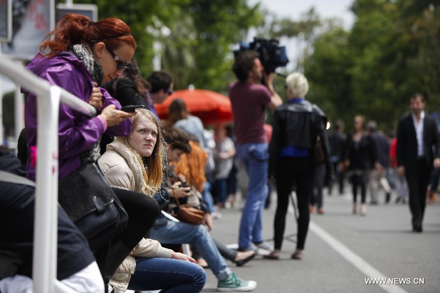 Movie fans wait to see the stars stepping on the red carpet during the 66th Cannes Film Festival in Cannes, France, on May 15, 2013. The film festival runs from May 15 to May 26 this year.(Xinhua/Zhou Lei) 