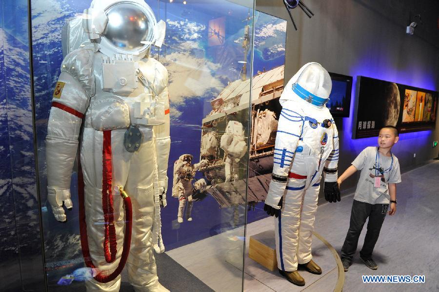 A boy views space suits during a scientific exhibition on lunar exploration in Guiyang, capital of southwest China's Guizhou Province, May 24, 2013. (Xinhua/Ou Dongqu)