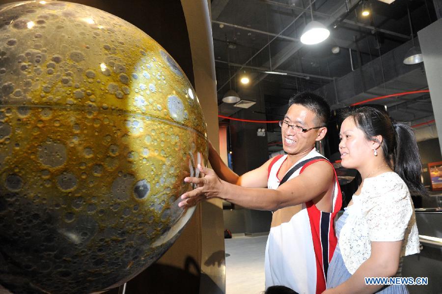 A visitor spins a moon globe whose image was pictured by China's moon orbiter Chang'e-1 during a scientific exhibition on lunar exploration in Guiyang, capital of southwest China's Guizhou Province, May 24, 2013. (Xinhua/Ou Dongqu)