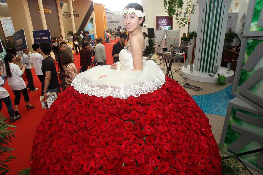 Photo taken on May 24, 2013 shows a girl wearing a skirt made by roses as a publicizing method to attract customers during the 55th Housing Fair held in Nantong City, east China's Jiangsu Province. The housing fair, featuring different kinds of publicizing methods, opened in the Nantong on Friday. (Xinhua/Cui Genyuan)