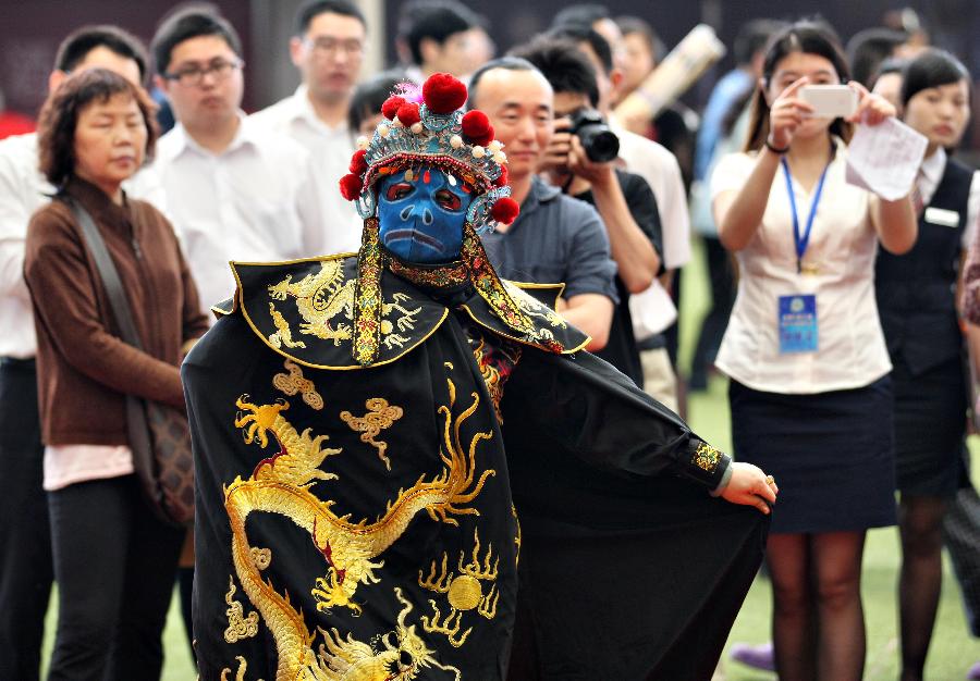 An art performer is invited to give face-changing shows to attract customers during the 55th Housing Fair held in Nantong City, east China's Jiangsu Province, May 24, 2013. The housing fair, featuring different kinds of publicizing methods, opened in the Nantong on Friday. (Xinhua/Cui Genyuan)