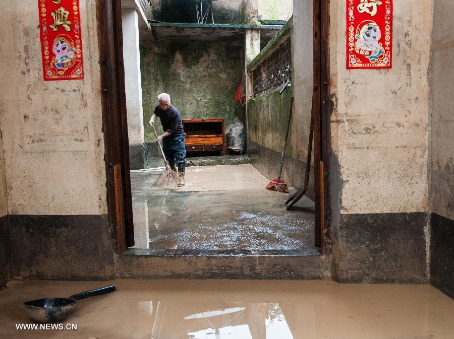 Zhong Yongxiang, 59, cleans his flooded house in Legan Village of Jiaoling County, Meizhou City, South China's Guangdong Province, May 23, 2013. Zhong has two sons, one suffering from cerebral palsy and another attending school outside their hometown, which makes life more difficult for Zhong after the rainstorm hitting Guangdong Province on May 18. With the youth attending school or working outside their hometowns, the left-behind family members are becoming even more vulnerable after natural disasters. (Xinhua/Mao Siqian)