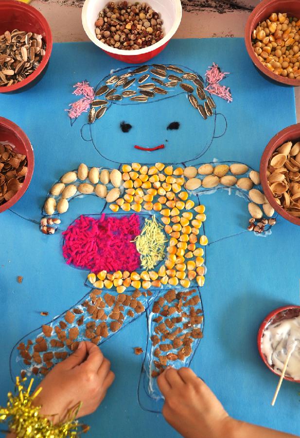 Children create a painting with cereals and crop shells at a kindergarten in Yuezhuang Town of Yiyuan County, east China's Shandong Province, May 24, 2013. Children here use waste materials to make toys to celebrate the coming Children's Day in a low-carbon way. (Xinhua/Zhao Dongshan)