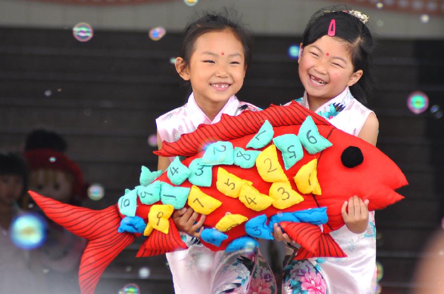 Children display a fish made of waste cloth at a kindergarten in Yuezhuang Town of Yiyuan County, east China's Shandong Province, May 24, 2013. Children here use waste materials to make toys to celebrate the coming Children's Day in a low-carbon way. (Xinhua/Zhao Dongshan)