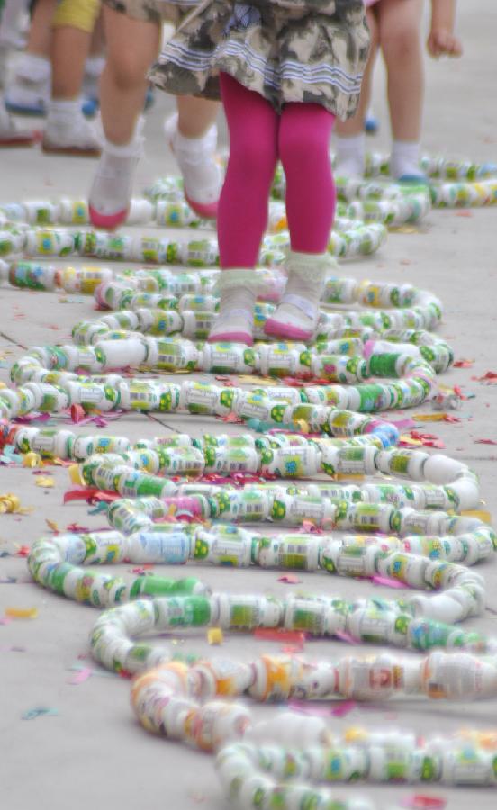Children play in circles made of wasted beverage bottles at a kindergarten in Yuezhuang Town of Yiyuan County, east China's Shandong Province, May 24, 2013. Children here use waste materials to make toys to celebrate the coming Children's Day in a low-carbon way. (Xinhua/Zhao Dongshan)
