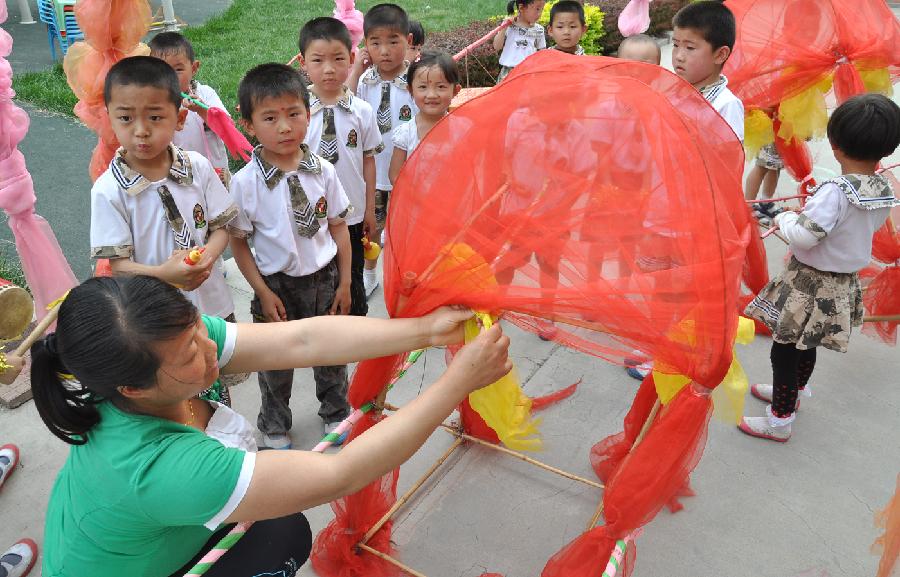Children make a sedan chair made of wasted materials with their teacher at a kindergarten in Yuezhuang Town of Yiyuan County, east China's Shandong Province, May 24, 2013. Children here use waste materials to make toys to celebrate the coming Children's Day in a low-carbon way. (Xinhua/Zhao Dongshan)