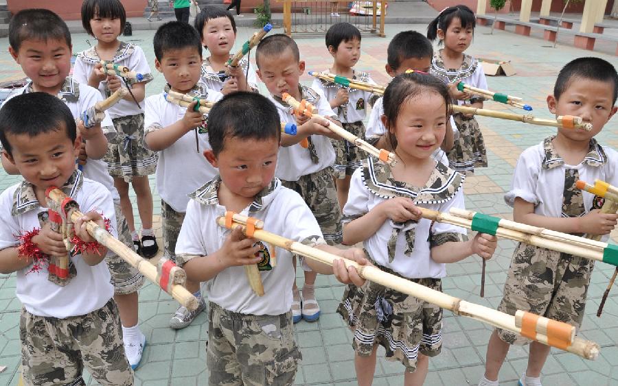 Children play with toy guns made of corn stalks at a kindergarten in Yuezhuang Town of Yiyuan County, east China's Shandong Province, May 24, 2013. Children here use waste materials to make toys to celebrate the coming Children's Day in a low-carbon way. (Xinhua/Zhao Dongshan)