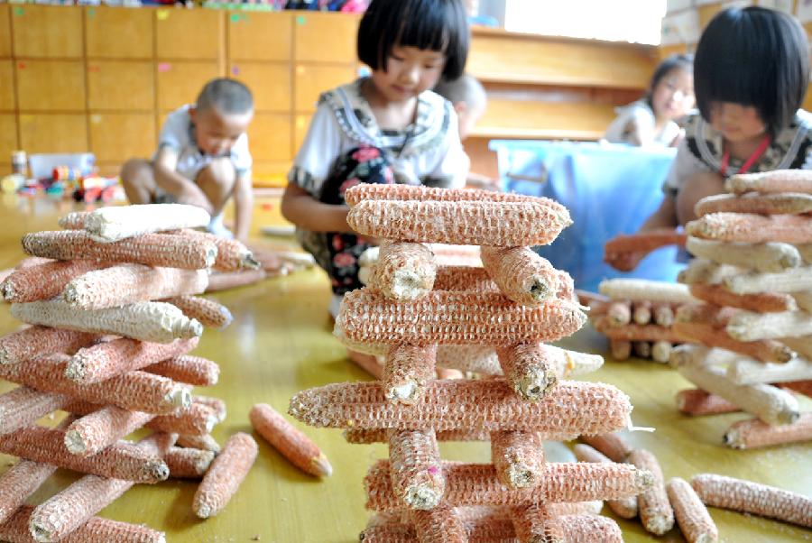 Children build towers with corncobs at a kindergarten in Yuezhuang Town of Yiyuan County, east China's Shandong Province, May 24, 2013. Children here use waste materials to make toys to celebrate the coming Children's Day in a low-carbon way. (Xinhua/Zhao Dongshan)