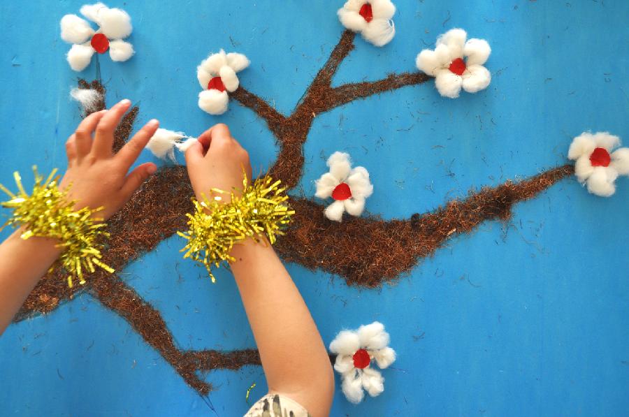 A child creates a painting with discarded wool and cotton at a kindergarten in Yuezhuang Town of Yiyuan County, east China's Shandong Province, May 24, 2013. Children here use waste materials to make toys to celebrate the coming Children's Day in a low-carbon way. (Xinhua/Zhao Dongshan)