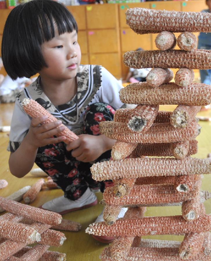 A child builds a tower with corncobs at a kindergarten in Yuezhuang Town of Yiyuan County, east China's Shandong Province, May 24, 2013. Children here use waste materials to make toys to celebrate the coming Children's Day in a low-carbon way. (Xinhua/Zhao Dongshan)