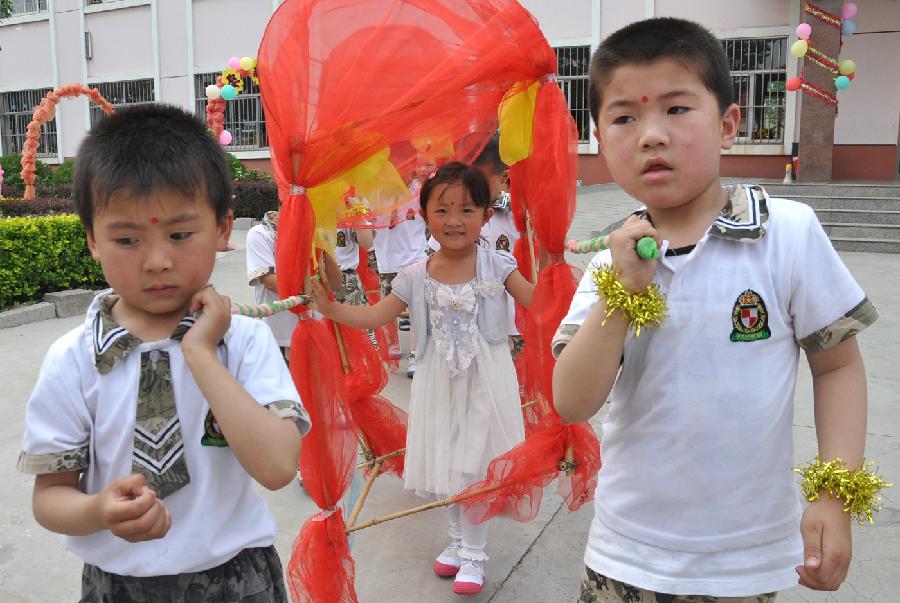 Children play with a sedan chair made of wasted materials at a kindergarten in Yuezhuang Town of Yiyuan County, east China's Shandong Province, May 24, 2013. Children here use waste materials to make toys to celebrate the coming Children's Day in a low-carbon way. (Xinhua/Zhao Dongshan)