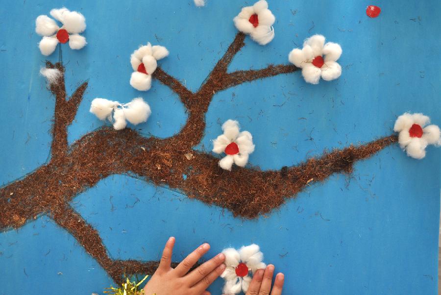 A child creates a painting with discarded wool and cotton at a kindergarten in Yuezhuang Town of Yiyuan County, east China's Shandong Province, May 24, 2013. Children here use waste materials to make toys to celebrate the coming Children's Day in a low-carbon way. (Xinhua/Zhao Dongshan)