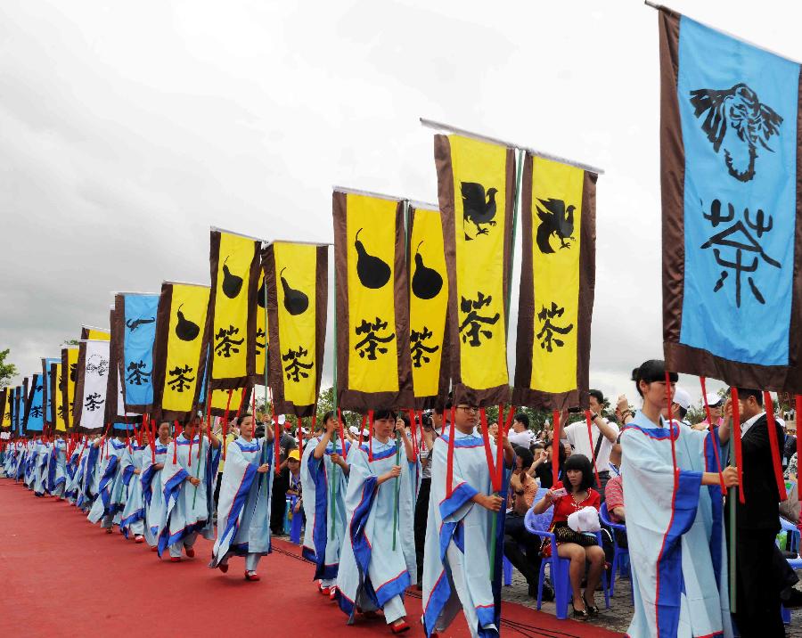 Local people in traditonal costumes hold giant banners with the Chinese character tea as they pay their tribute to the ancestor of tea during the opening of 2013 International Tea Convention in Pu'er, southwest China's Yunnan Province, May 25, 2013. The convention that opened on Saturday aims to promote tea culture around the world. (Xinhua/Yang Zongyou)