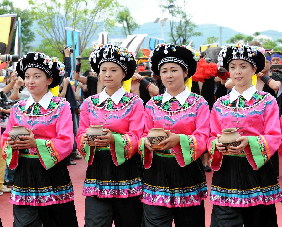 Local people in traditonal costumes hold a jar of water as they pay their tribute to the ancestor of tea during the opening of 2013 International Tea Convention in Pu'er, southwest China's Yunnan Province, May 25, 2013. The convention that opened on Saturday aims to promote tea culture around the world. (Xinhua/Yang Zongyou)