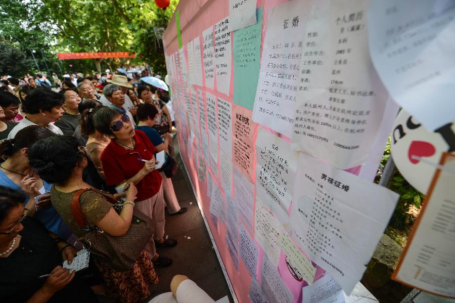 People view marriage-seeking leaflets during a blind date event at Huanglongdong scenic area in Hangzhou, capital of east China's Zhejiang Province, May 25, 2013. The event attracted over 5,000 participants, including both young singles and their parents. (Xinhua/Xu Yu)