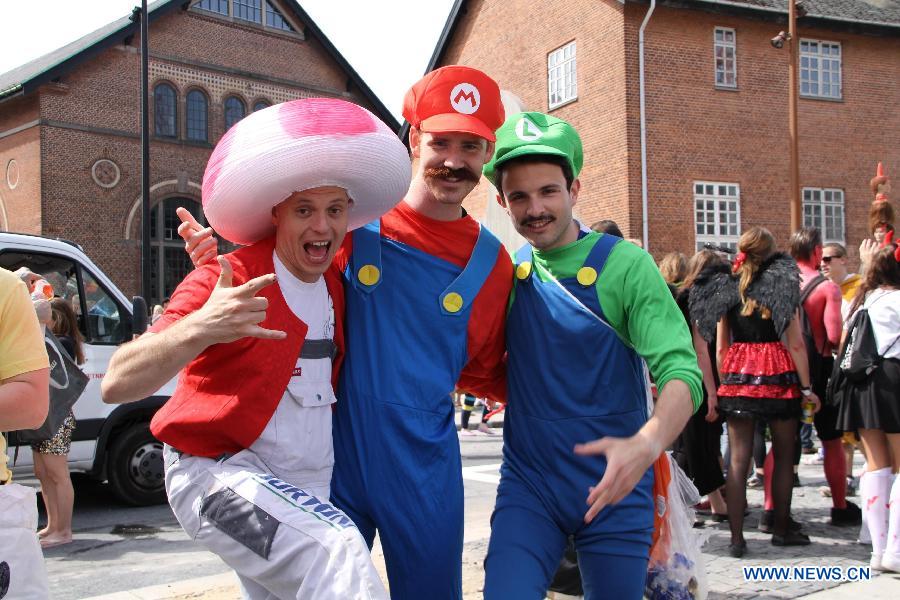 Three revellers joining in a carnival parade pose for photos during the Aalborg Carnival in Aalborg, on May 25, 2013. The nine-day festive event started on May 17. (Xinhua/Yang Jingzhong)