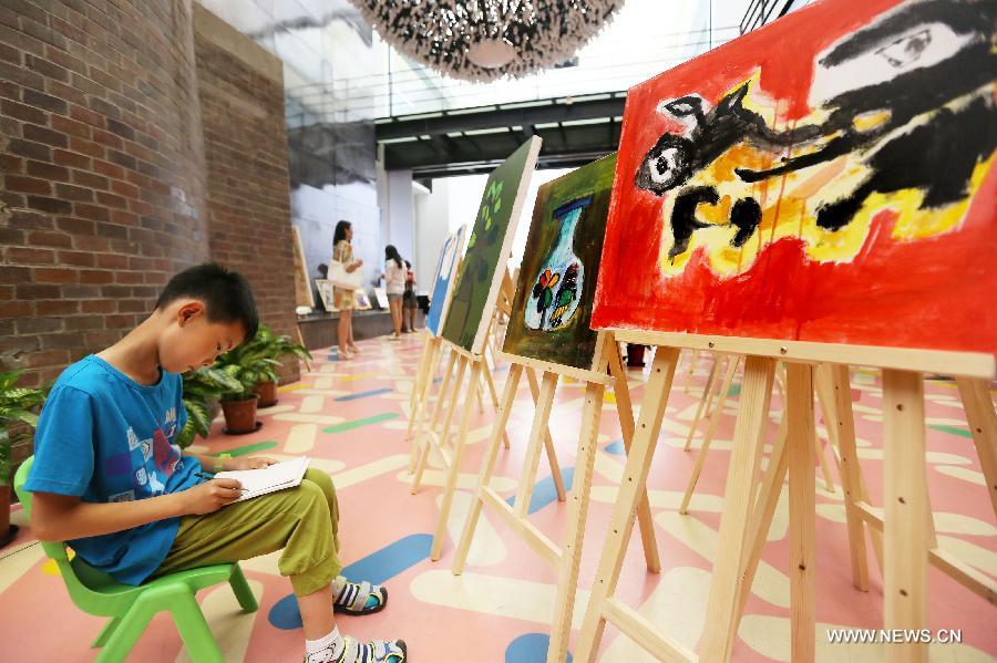 A child copies paintings at a painting exhibition at the 798 art area in Beijing, capital of China, May 25, 2013. A two-day exhibition kicked off on Saturday, displaying paintings created by over 20 mentally retarded children from Chaoyang Anhua School. (Xinhua) 