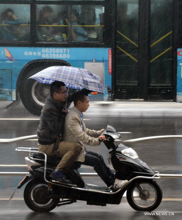 Local residents ride in rain in Zhengzhou, capital of central China's Henan Province, May 26, 2013. Many parts in Henan witnessed rainfall since Saturday. Local meteorological authorities issued a yellow alert on thunder.(Xinhua/Wang Song)