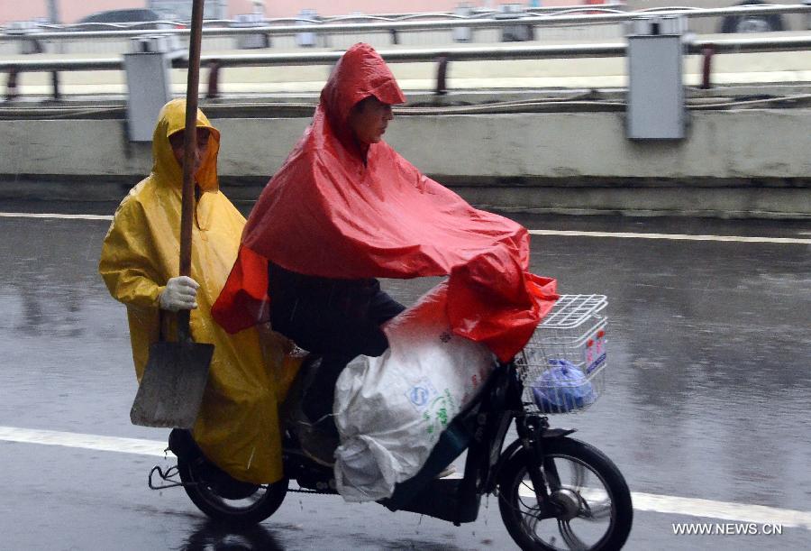 Local residents ride in rain in Zhengzhou, capital of central China's Henan Province, May 26, 2013. Many parts in Henan witnessed rainfall since Saturday. Local meteorological authorities issued a yellow alert on thunder.(Xinhua/Wang Song)