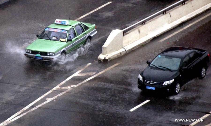 Cars pass a water accumulated area caused by rain in Zhengzhou, capital of central China's Henan Province, May 26, 2013. Many parts in Henan witnessed rainfall since Saturday. Local meteorological authorities issued a yellow alert on thunder.(Xinhua/Wang Song)