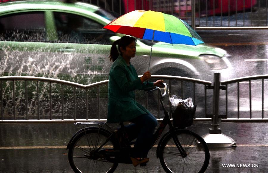 A woman rides in rain in Zhengzhou, capital of central China's Henan Province, May 26, 2013. Many parts in Henan witnessed rainfall since Saturday. Local meteorological authorities issued a yellow alert on thunder.(Xinhua/Wang Song)
