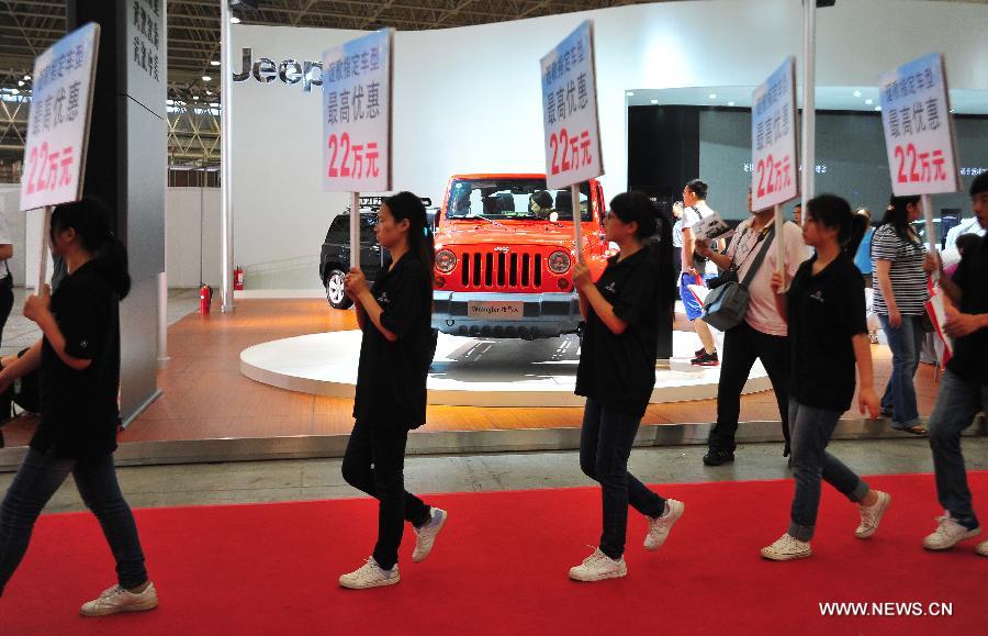 Staff members holding boards with special offers walk at an auto show in Wuhan, capital of central China's Hubei Province, May 26, 2013. The four-day auto show, which kicked off on Saturday, attracted more than 70 auto brands. (Xinhua/Xiao Yijiu) 