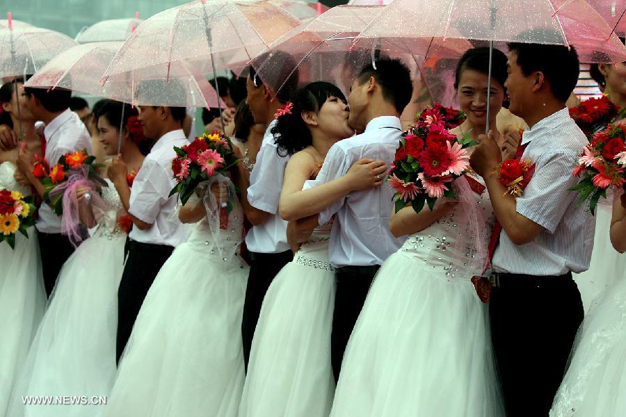 Newly-wed couples are seen at a group wedding ceremony for migrant workers in Jinan, capital of east China's Shandong Province, May 26, 2013. A group wedding was held for migrant workers here on Sunday, with 31 pairs of newly-wed couples participating. (Xinhua/Cui Jian)