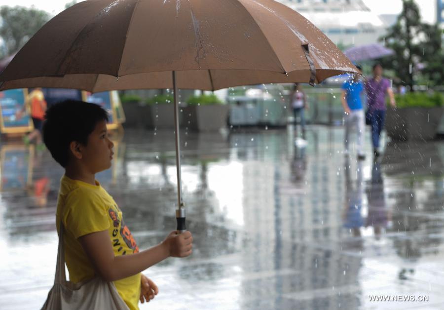 A boy holds an umbrella amid rain in Shenzhen, south China's Guangdong Province, May 26, 2013. Torrential rain hit most parts of Guangdong Province from Saturday to Sunday. (Xinhua/Mao Siqian)
