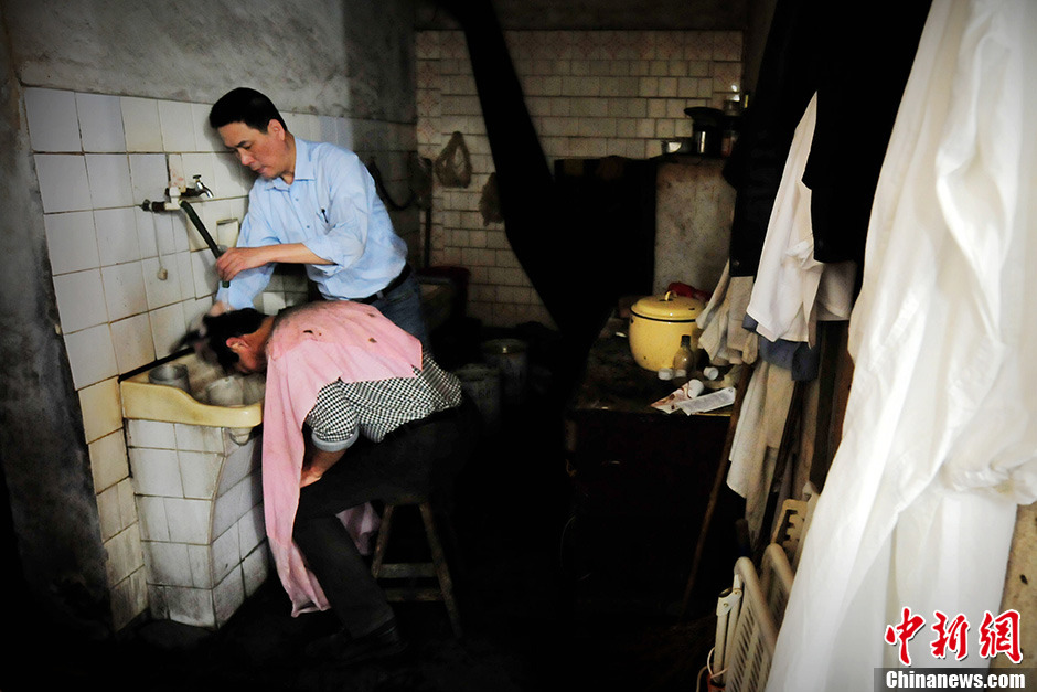 Chen Shuiping, a 59-year-old barber, washes a client's hair in the barbershop. （Photo/Chinanews）