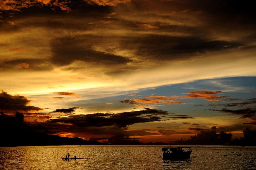 Fishermen paddle a traditional boat during sunset at Waiara beach in Maumere on Flores island in East Nusa Tenggara on May 20, 2013.  (Xinhua/AFP Photo)