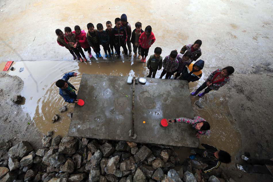 Pupils play table tennis on a simple and crude table surrounded by water in Nonglei primary school in Guangxi. Due to the serious lack of teachers, facilities and equipment, PE lessons is just a dream for many rural children. (Xinhua Photo/ Huang Xiaobang)