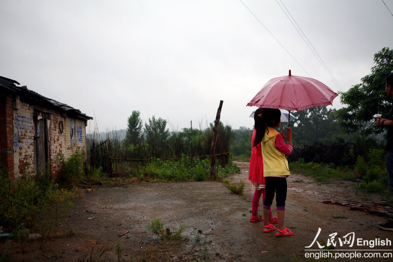 Two students wait for a bus to the Maoji county health center to receive medical evaluations in order to determine how much physical damage was inflicted on them by their teacher in Douchengou village, Huanggang town of Tongbai county in Nanyang city of Central China's Henan province on May 26, 2013. [Photo/CFP]