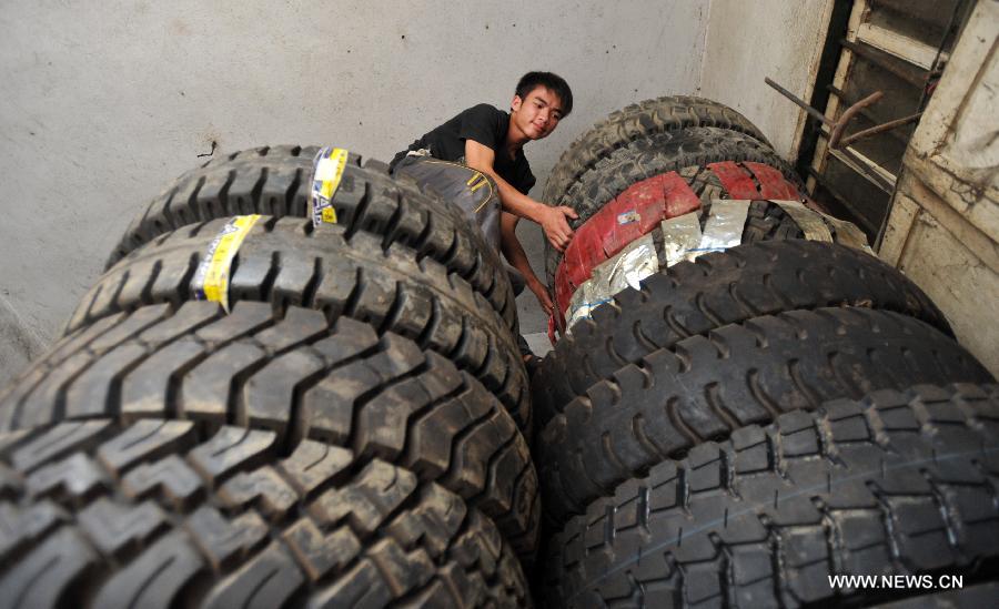 Lan Chuan arranges tires at Fozi Village in Shanglin County of Nanning City, capital of southwest China's Guangxi Zhuang Autonomous Region, May 26, 2013. Lan, a 15-year-old middle school student, lives with his paralyzed father on fixing farming machines. Without the care of mother who left the family when he was three years old, Lan takes care of his father and supports his family by aiding him with the fixing work. His story has moved many people in the region, which also brought him the title of "juvenile of virtues " of Nanjing in 2012. (Xinhua/Lu Boan)