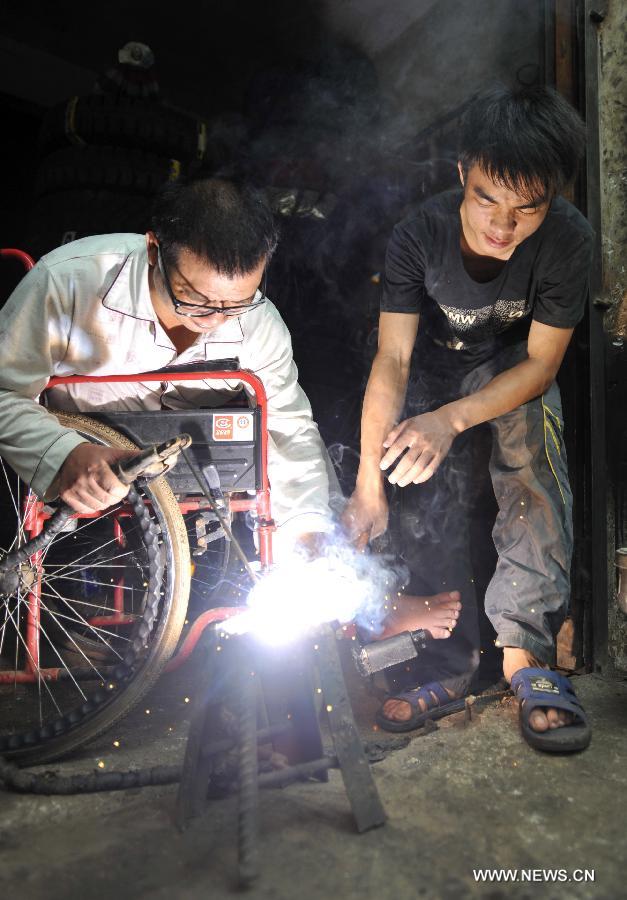 Lan Chuan (R) and his father Lan Zhongguo joint a machine part at Fozi Village in Shanglin County of Nanning City, capital of southwest China's Guangxi Zhuang Autonomous Region, May 26, 2013. Lan, a 15-year-old middle school student, lives with his paralyzed father on fixing farming machines. Without the care of mother who left the family when he was three years old, Lan takes care of his father and supports his family by aiding him with the fixing work. His story has moved many people in the region, which also brought him the title of "juvenile of virtues " of Nanjing in 2012. (Xinhua/Lu Boan)