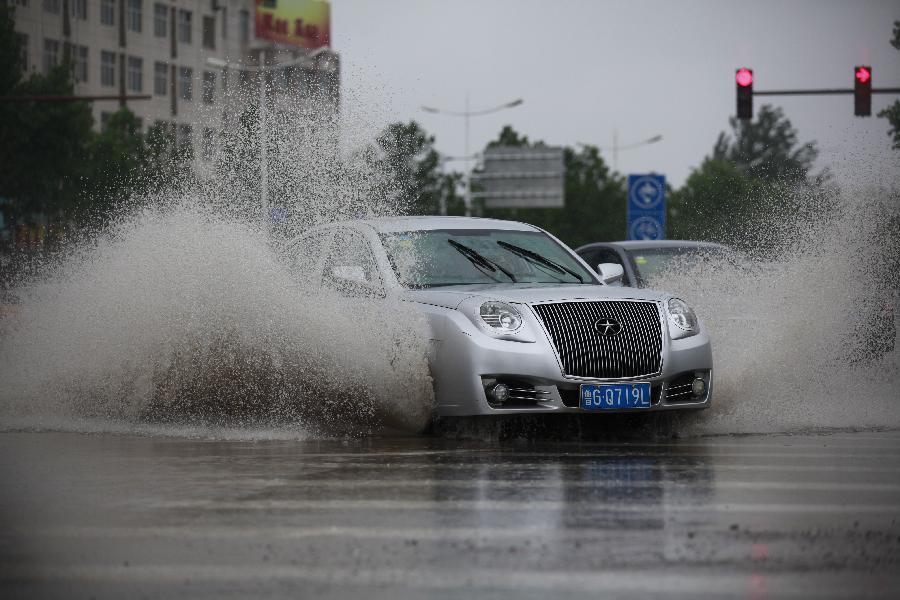 A car drives on a flooded road in Heze City, east China's Shandong Province, May 26, 2013. A heavy rainfall hit Shandong Province as of May 25, with the average rainfall reaching 80.2 millimeters by May 26. (Xinhua/Zhou Donglun)